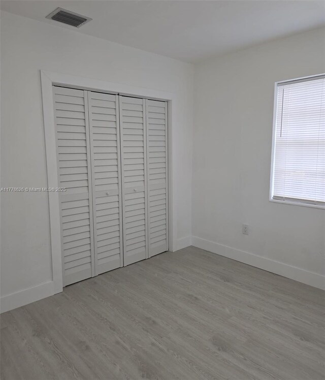 3242 NW 87th Ter, Miami, FL 33147 - unfurnished bedroom featuring baseboards, wood finished floors, a closet, and visible vents