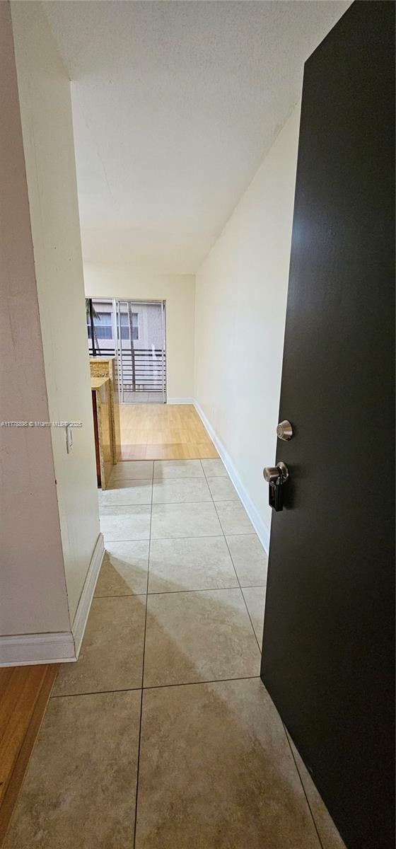 corridor featuring light tile patterned floors and baseboards