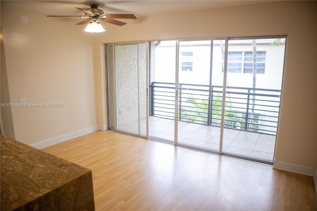 spare room with wood finished floors, baseboards, and a ceiling fan