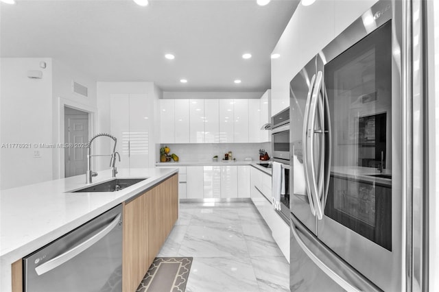 kitchen featuring modern cabinets, visible vents, appliances with stainless steel finishes, marble finish floor, and a sink