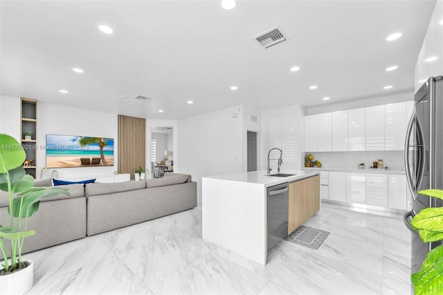 kitchen with modern cabinets, white cabinets, visible vents, stainless steel appliances, and a center island with sink
