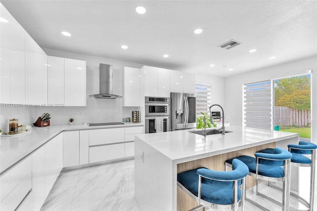 kitchen with modern cabinets, a sink, wall chimney range hood, stainless steel appliances, and marble finish floor