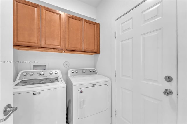 clothes washing area with washing machine and clothes dryer and cabinet space
