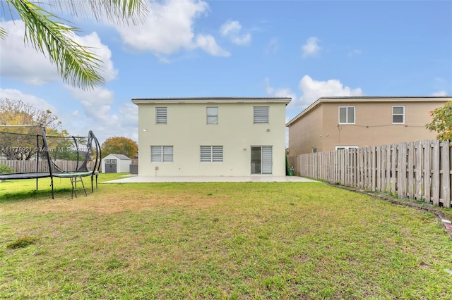 back of property with a patio area, a trampoline, and a lawn