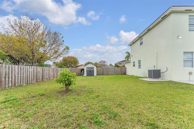 view of yard with a storage shed, a fenced backyard, cooling unit, and an outbuilding