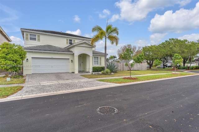 traditional-style house with a garage, decorative driveway, fence, and a front lawn