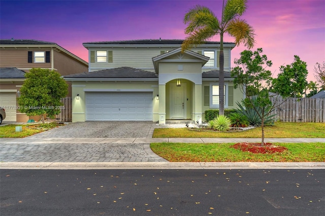 traditional-style home featuring decorative driveway, stucco siding, and fence