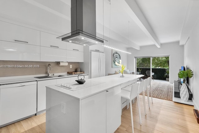 kitchen with white cabinets, modern cabinets, a sink, white appliances, and island exhaust hood