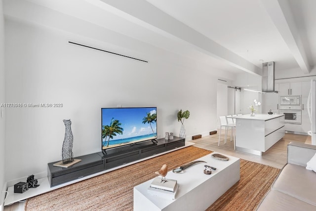 living area featuring light wood-type flooring, beamed ceiling, and baseboards