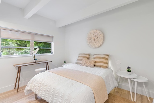 bedroom featuring baseboards, beamed ceiling, and wood finished floors