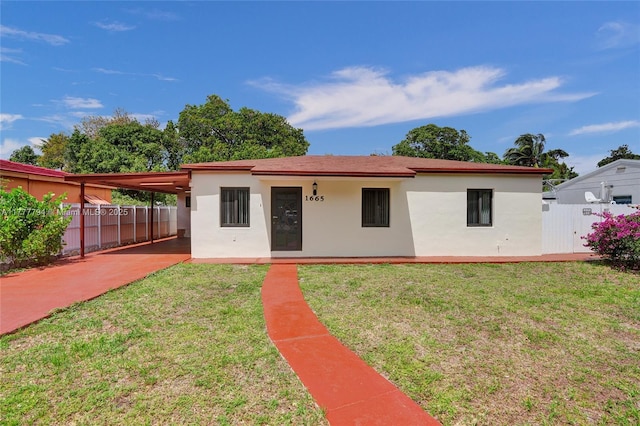 rear view of property with a carport, a yard, and fence