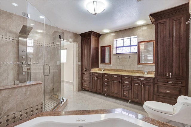 full bathroom featuring tile walls, toilet, a shower stall, double vanity, and a garden tub