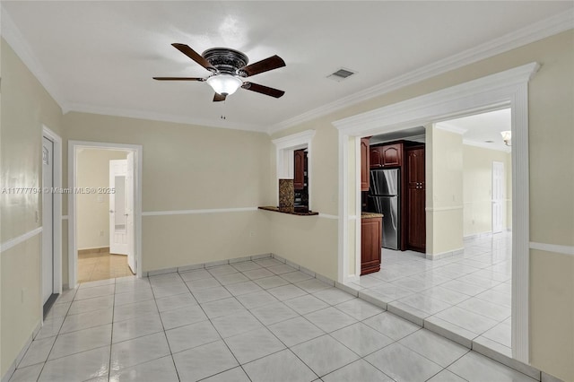 empty room with crown molding, visible vents, a ceiling fan, and light tile patterned floors