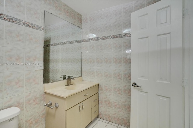 bathroom featuring toilet, tile patterned floors, vanity, and tile walls