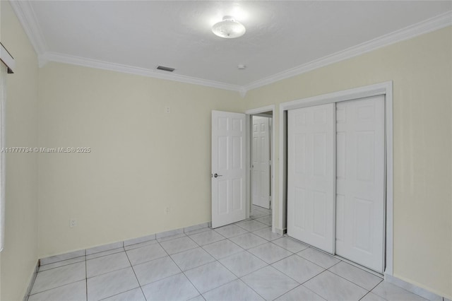 unfurnished bedroom with crown molding, a closet, light tile patterned floors, and visible vents