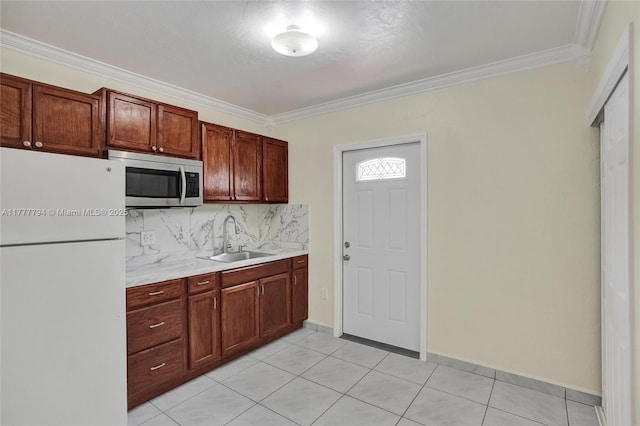 kitchen with stainless steel microwave, tasteful backsplash, light countertops, freestanding refrigerator, and a sink