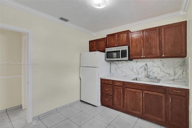kitchen with freestanding refrigerator, visible vents, stainless steel microwave, light countertops, and a sink