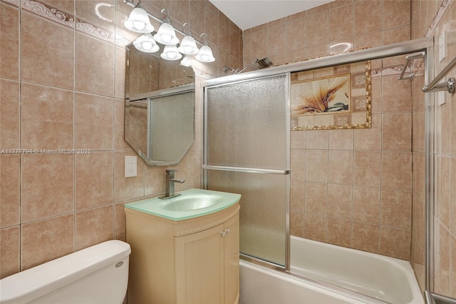 full bathroom with toilet, vanity, combined bath / shower with glass door, and tile walls