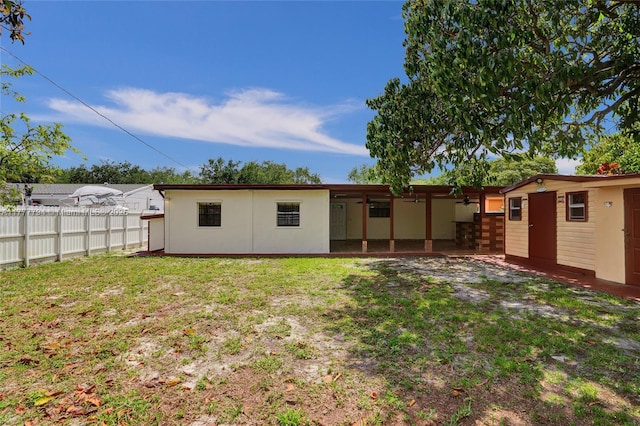 back of house featuring stucco siding, a ceiling fan, a patio area, fence, and a lawn