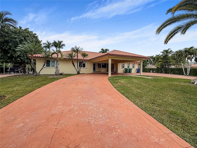 view of front of property featuring a tiled roof, a front yard, curved driveway, and stucco siding