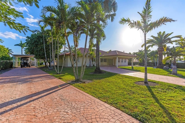 ranch-style home featuring an attached carport, a front yard, and decorative driveway