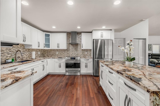 kitchen featuring wall chimney exhaust hood, stainless steel appliances, a sink, white cabinetry, and glass insert cabinets
