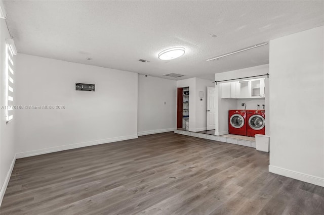 unfurnished living room with wood finished floors, visible vents, baseboards, separate washer and dryer, and a textured ceiling