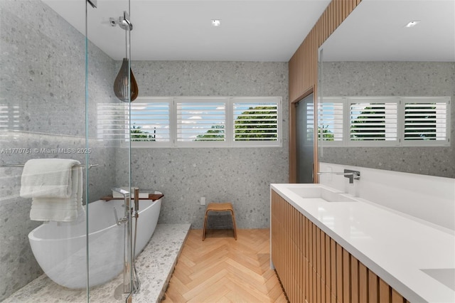 bathroom with a soaking tub, double vanity, a sink, and wallpapered walls