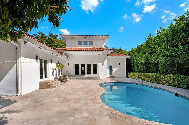 back of house featuring a patio, stucco siding, an outdoor pool, french doors, and a tile roof