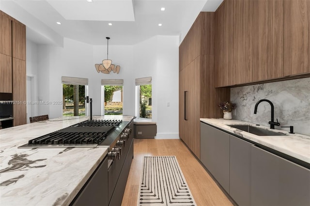 kitchen featuring light wood-style flooring, a sink, modern cabinets, and light stone countertops