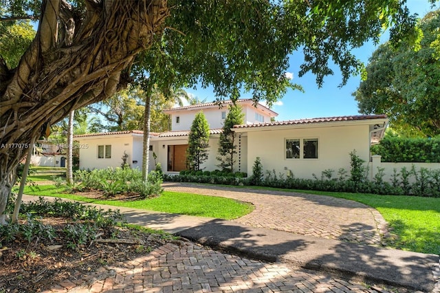 mediterranean / spanish house featuring a tile roof and stucco siding