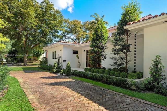 exterior space with stucco siding and a tile roof
