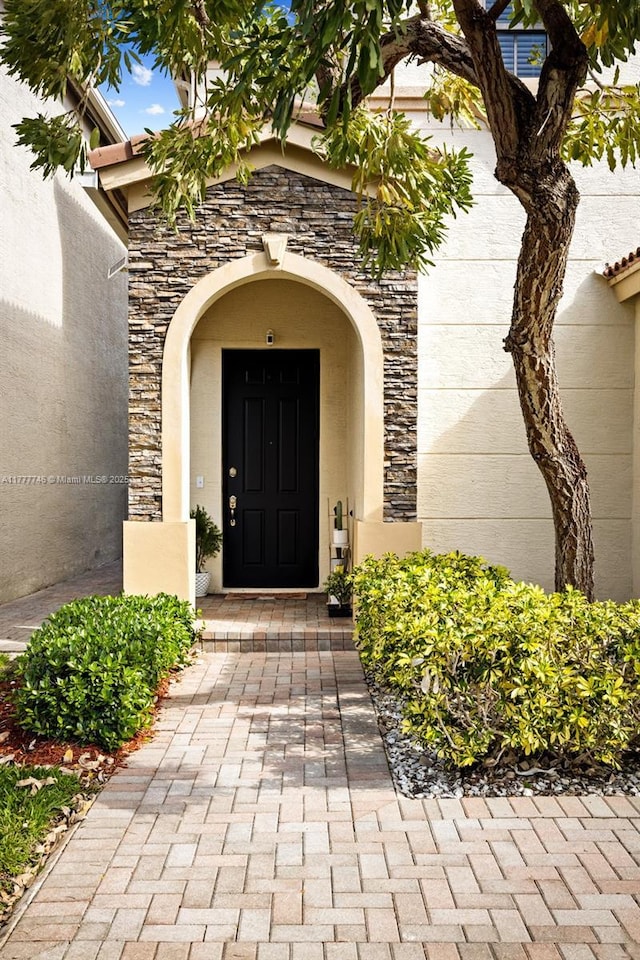 property entrance featuring stucco siding and stone siding