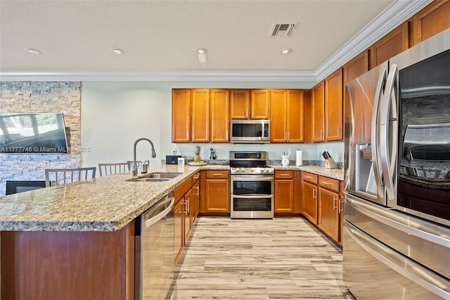 kitchen with crown molding, visible vents, a sink, stainless steel appliances, and brown cabinets