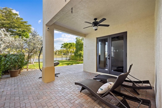 view of patio / terrace featuring fence, french doors, and a ceiling fan
