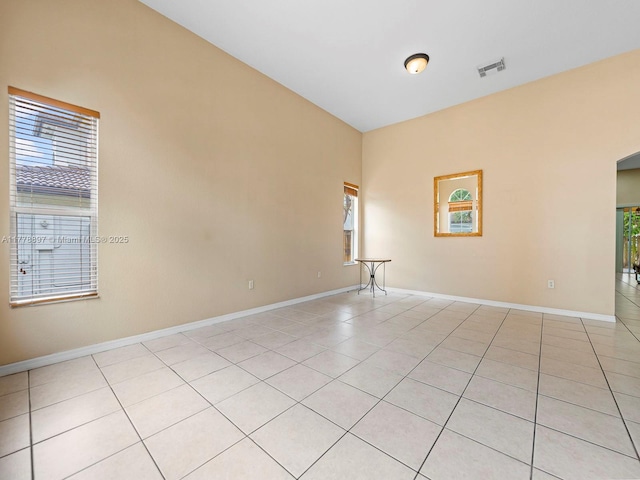 spare room featuring visible vents, baseboards, arched walkways, and light tile patterned floors