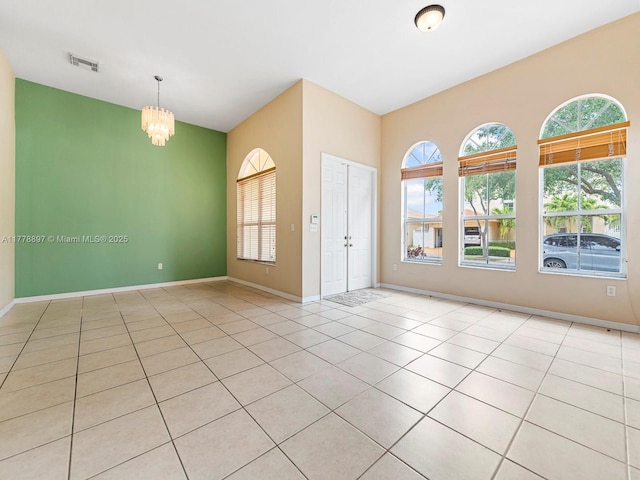 unfurnished room with a chandelier, light tile patterned flooring, baseboards, and visible vents