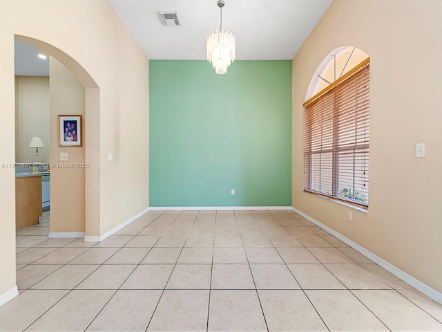 spare room with visible vents, baseboards, arched walkways, and a notable chandelier