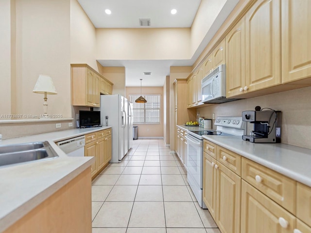 kitchen featuring light tile patterned floors, white appliances, visible vents, a sink, and light brown cabinets