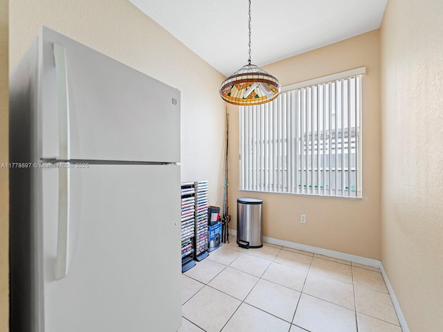 unfurnished dining area with baseboards and tile patterned flooring