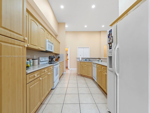kitchen with light tile patterned floors, light brown cabinets, light countertops, white appliances, and recessed lighting