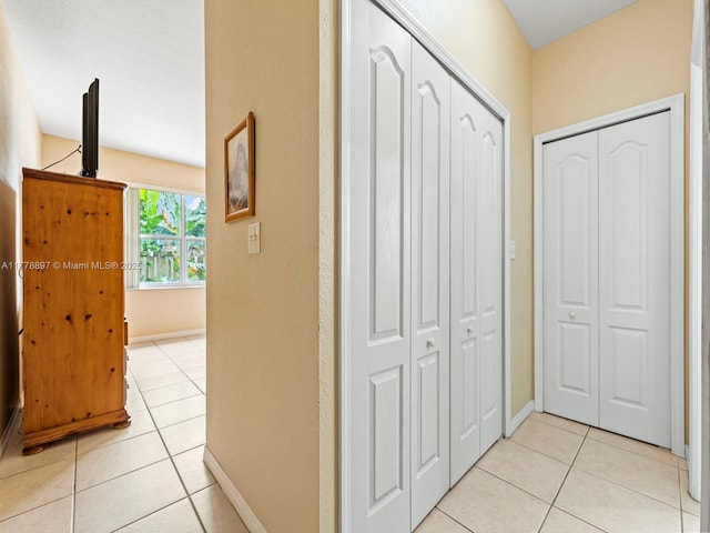 corridor featuring light tile patterned floors and baseboards