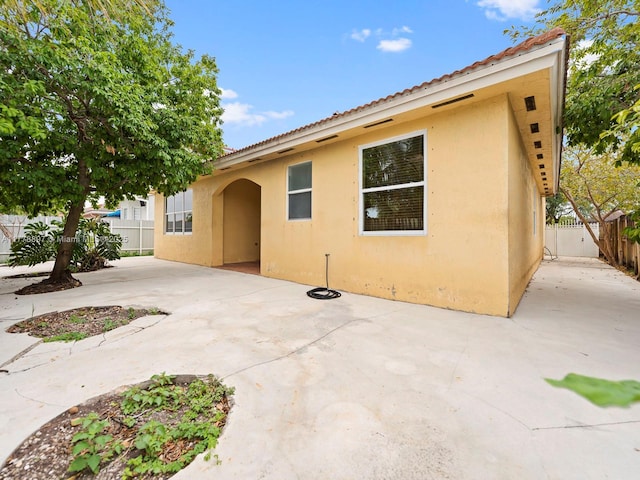 rear view of property with a patio, stucco siding, and fence