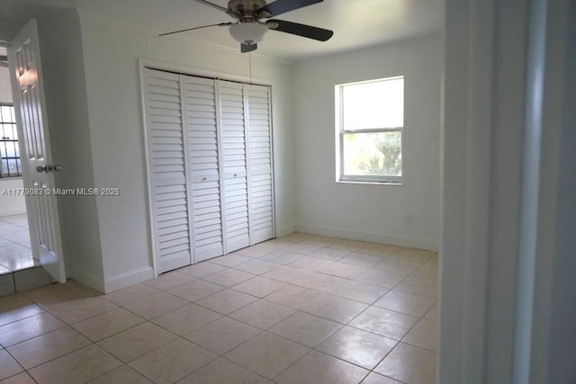 unfurnished bedroom with ceiling fan, a closet, light tile patterned floors, and baseboards