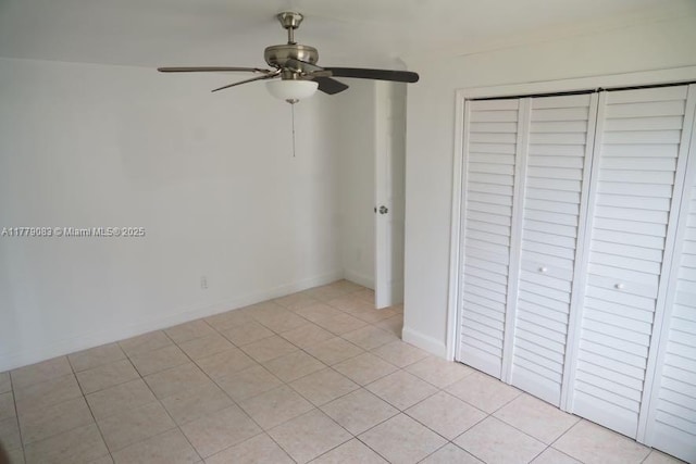 unfurnished bedroom with ceiling fan, a closet, light tile patterned floors, and baseboards