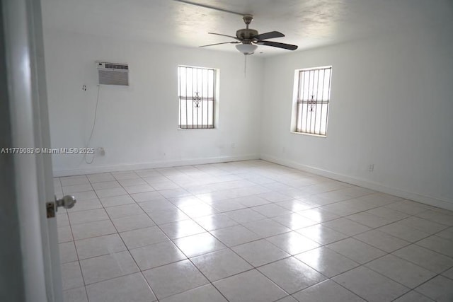 spare room featuring a healthy amount of sunlight, ceiling fan, baseboards, and a wall mounted air conditioner