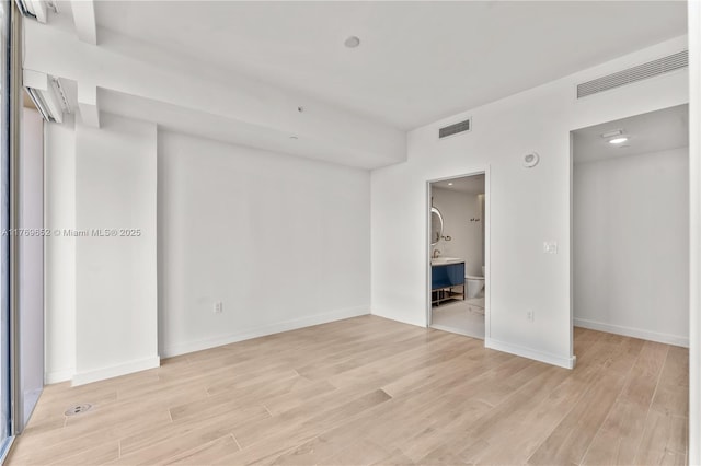 spare room with light wood-type flooring, baseboards, and visible vents
