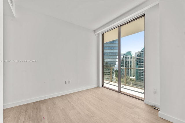 spare room featuring baseboards, light wood-style floors, and a city view