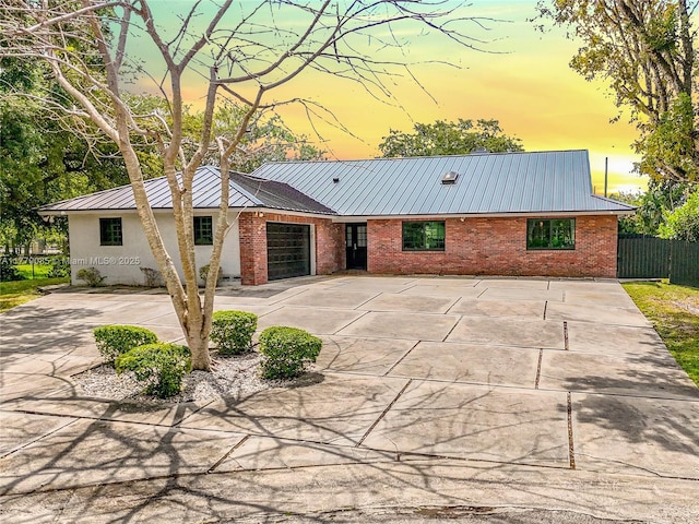 ranch-style home featuring brick siding, fence, and metal roof