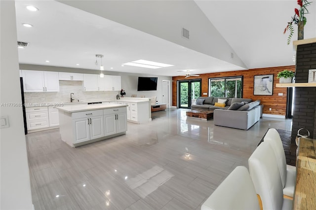 kitchen featuring light countertops, white cabinetry, a kitchen island, decorative backsplash, and a sink